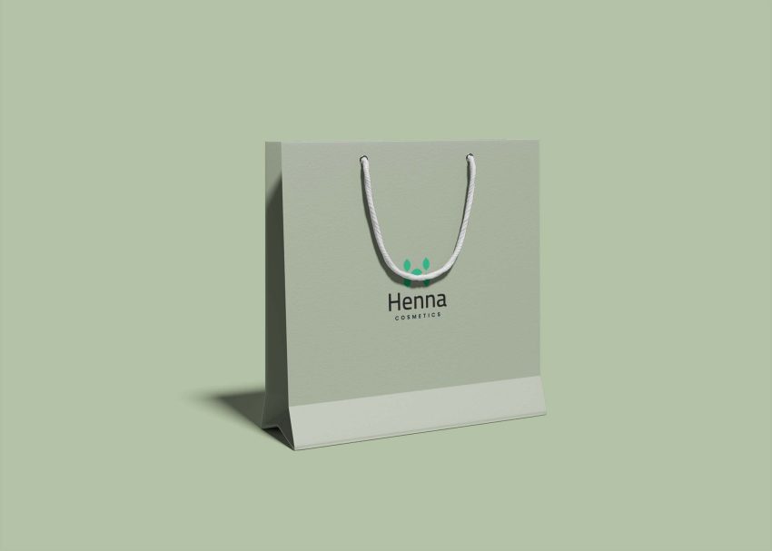 A light green shopping bag with a white handle displays the logo "Henna Cosmetics" on its front.