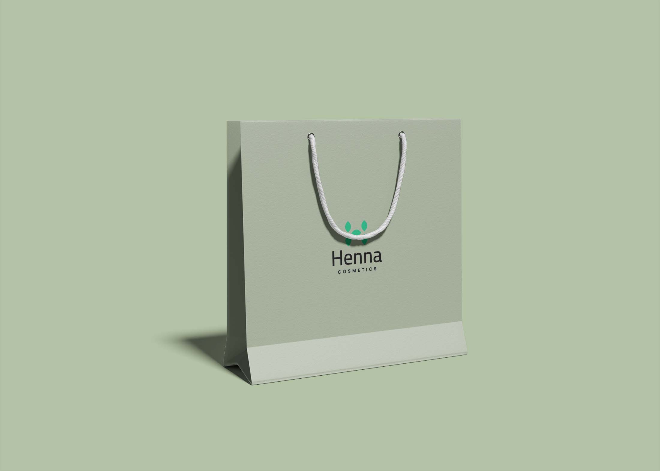 A light green shopping bag with a white handle displays the logo "Henna Cosmetics" on its front.