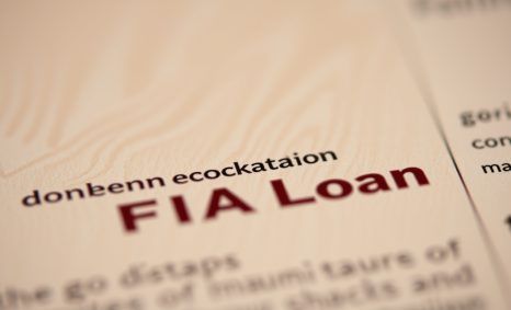 Close-up of a document highlighting "FHA Loan" in bold maroon text on a light wood background with additional text below