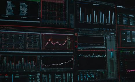 A dark room filled with multiple screens displaying colorful graphs, charts, and data analytics related to digital growt